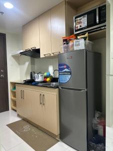 een keuken met een roestvrijstalen koelkast en kasten bij Family room at Brenthill Condo Near SM and Botanical Garden in Baguio