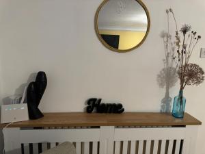 uno specchio su una parete bianca con un tavolo in legno di Vista Lodge a Wythenshawe