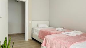 two beds in a white room with pink sheets at Nova City Center in Divjakë