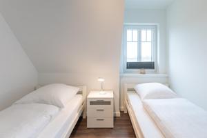 2 bedden in een witte kamer met een raam bij Utsicht in Nordstrand