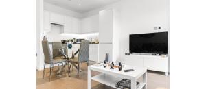 uma sala de estar branca com uma mesa e uma televisão em Metropolitan Luxury: Chic 2BR Flat in St. Albans em Saint Albans
