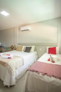 two beds in a hotel room with white walls at Pousada Praiana in Porto De Galinhas
