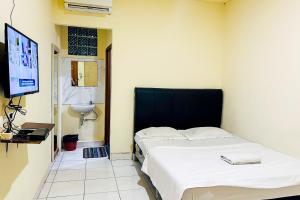Habitación con 2 camas y TV. en Wisma Berkat Mitra RedDoorz, en Yakarta