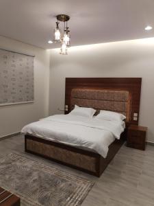 a bedroom with a large bed and a chandelier at شقق الياسمين in Al Madinah