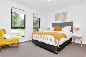 a white bedroom with a bed and a yellow chair at Entire home in Mount Barker in Mount Barker