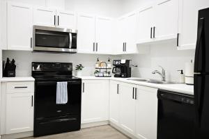 a kitchen with white cabinets and black appliances at Stylish Retreat with King Bed, Long Stays, WEM, Disney+ in Edmonton