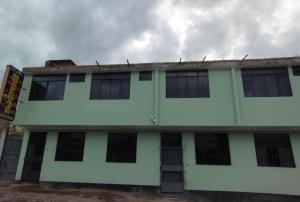 un edificio blanco con ventanas de barrotes negros. en Hospedaje LOS OLIVOS, en Ayacucho