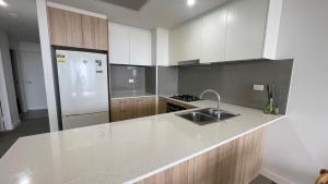 a kitchen with a white refrigerator and a sink at Parramatta New Paint 2B2B High Floor apt next to Train and shopping in Sydney