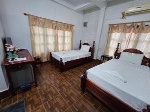 a bedroom with two beds and a desk and a tv at Maylayguesthouse1 in Vang Vieng