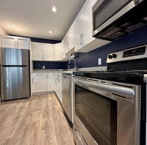 a kitchen with stainless steel appliances and white cabinets at Life house loft in Sooke