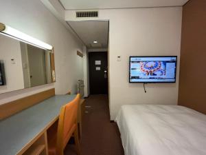 um quarto de hospital com uma cama e uma televisão na parede em Hotel Alpha-One Tottori em Tottori