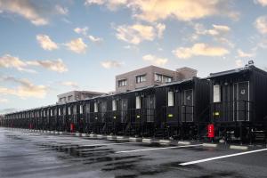 una fila di vagoni ferroviari neri parcheggiati in un parcheggio di HOTEL R9 The Yard 松阪 a Matsuzaka