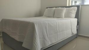 Una cama con sábanas blancas y almohadas. en Hermoso apartamento, moderno, club house, excelente ubicación!,, en Neiva