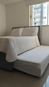 ein Bett mit weißer Bettwäsche und Kissen darauf in der Unterkunft Hermoso apartamento, moderno, club house, excelente ubicación!, in Neiva