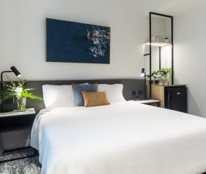 a bedroom with a large white bed and a mirror at Oaks Cairns Hotel in Cairns