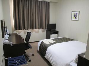 a hotel room with a bed and a desk and a computer at Okawa Riverside Hotel in Ōkawa