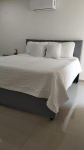 Una cama con sábanas blancas y almohadas en un dormitorio en Hermoso apartamento, moderno, club house, excelente ubicación!,, en Neiva