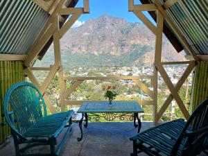 a table and chairs on a porch with a view of a mountain at Las Cabañas De Mike in San Juan La Laguna