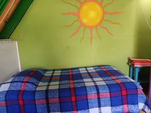 a bedroom with a bed with a sun painted on the wall at Las Cabañas De Mike in San Juan La Laguna
