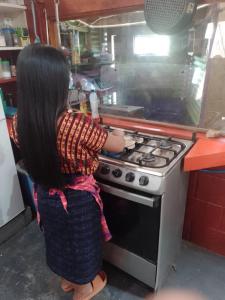 a young girl is cooking on a stove in a kitchen at Las Cabañas De Mike in San Juan La Laguna