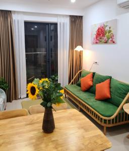 a living room with a green couch and a vase with flowers at Ina apartment - Nera garden Hue in Hue