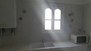 a white kitchen with a sink and a window at Joli Appartment A Zitouna 2 in Port El Kantaoui