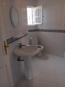 a white bathroom with a sink and a toilet at Joli Appartment A Zitouna 2 in Port El Kantaoui