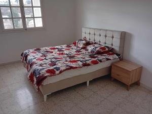 a bed in a bedroom with a quilt and a table at Joli Appartment A Zitouna 2 in Port El Kantaoui