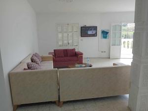 uma sala de estar com um sofá grande e duas cadeiras em Joli Appartment A Zitouna 2 em Port El Kantaoui
