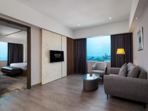 ASTON Makassar Hotel & Convention Center في ماكاسار: غرفة معيشة مع أريكة وغرفة مع سرير