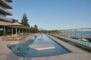 una piscina con mesas y sillas y la playa en Kirra Point Holiday Apartments en Coolangatta