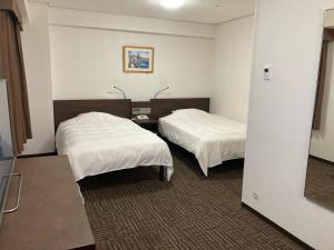 a hotel room with two beds with white sheets at Hotel Alpha-One Tsuyama in Tuyama