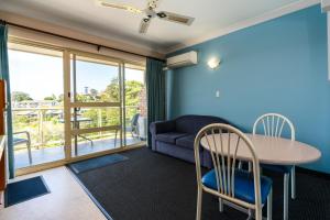 ein Wohnzimmer mit einem Tisch, Stühlen und einem Sofa in der Unterkunft Sapphire Waters Motor Inn in Merimbula