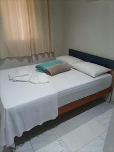 1 cama grande con sábanas blancas y almohadas. en Cantinho Aconchego en Santo Antônio do Pinhal