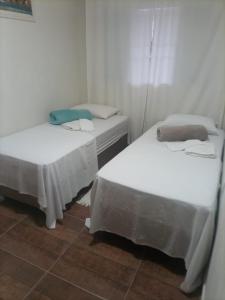 two beds in a room with white walls at Cantinho Aconchego in Santo Antônio do Pinhal