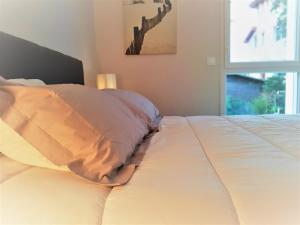 a white bed with a pillow and a window at Appartement moderne 3* avec balcon, proche du lac et plage, parking privatif, Wi-Fi inclus - FR-1-239-862 in Soorts-Hossegor
