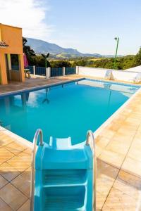 - une piscine bleue avec une chaise devant dans l'établissement Sua casa na Serra da Mantiqueira. 1h de SP, à Extrema