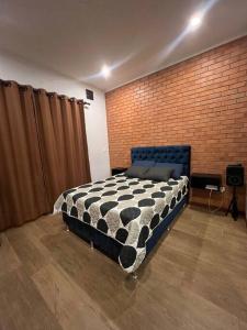 Un dormitorio con una cama en blanco y negro y una pared de ladrillo en Cómodo céntrico y acogedor apartamento, en Tarija