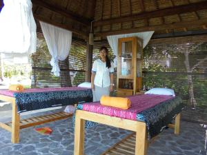 a woman standing in a room with two beds at Amarta Beach Cottages in Candidasa