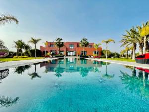 a large swimming pool with palm trees and a building at Villa Dar El Hna in Marrakesh +11 photos
