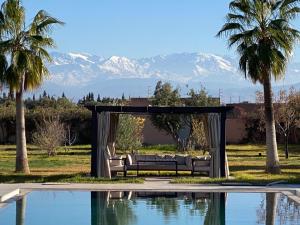 a bench next to a pool with mountains in the background at Villa Dar El Hna in Marrakesh