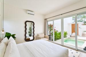 a bedroom with a white bed and a large window at Elena Villa by Betterplace in Tanah Lot