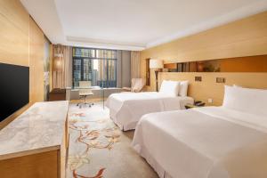 a hotel room with two beds and a desk at The Westin Bund Center, Shanghai in Shanghai