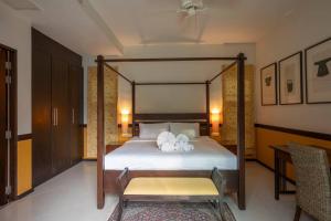 een slaapkamer met een hemelbed en een tafel bij Summer Dream 3-Bedroom pool villa in Ban Saiyuan (1)