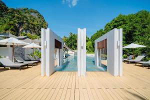 a pool with chairs and umbrellas on a wooden deck at Bhu Nga Thani Resort & Villas Railay in Railay Beach