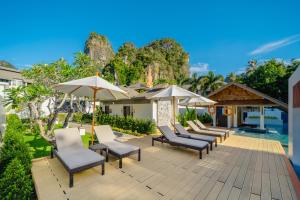 a deck with chairs and umbrellas and the water at Bhu Nga Thani Resort & Villas Railay in Railay Beach