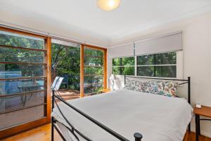 a bedroom with a bed and large windows at King Parrot in Pearl Beach