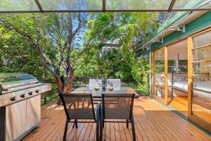 a patio with a table and chairs and a stove at King Parrot in Pearl Beach