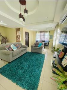 una sala de estar con 2 sofás y una alfombra verde en Travelholics Getaways, en Piarco
