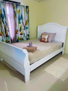 ein weißes Bett mit ausgestopftem Tier auf einem Zimmer in der Unterkunft Travelholics Getaways in Piarco